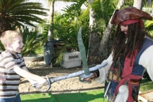 picture of a jack sparrow impersonator with kids in a sword fighting game and sword training at a pirate theme birthday party